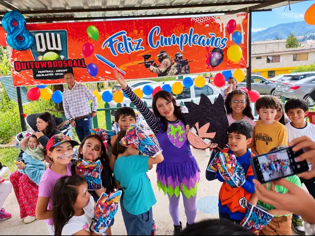 Fiesta de cumpleaños infantil en Quito Woodsball: niños con la animadora bajo el letrero de Feliz Cumpleaños con globos de colores